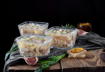 Holodets with chicken and pork meat in glass portion bowls against the dark background
