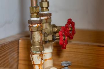 PVC plastic plumbing water pipe with brass valve leaking and corroded at threads and stem packing. Concept of DYI home maintenance, repair, remodeling