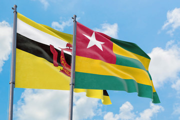 Togo and Brunei flags waving in the wind against white cloudy blue sky together. Diplomacy concept, international relations.