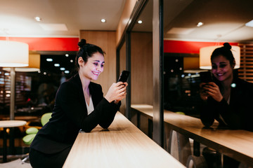 young woman using mobile phone in a cafe or restaurant indoors. Technology and lifestyle