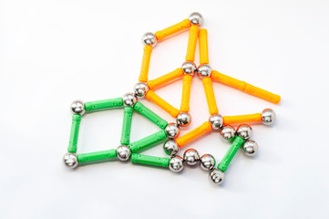 Children's magnetic constructor sticks and metal balls on a white background with copy space. Children's sensory game, child development, logic