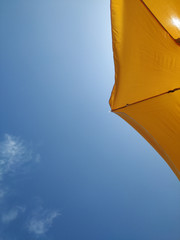Sombrilla amarilla bajo el cielo azul en la playa durante vacaciones