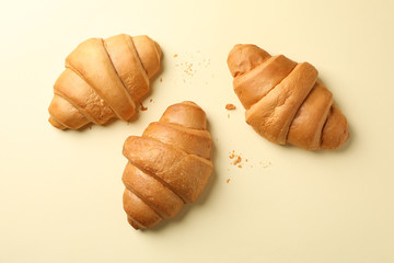 Baked croissants on beige background, top view