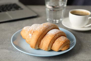 Composition with croissant and computer on grey table, close up
