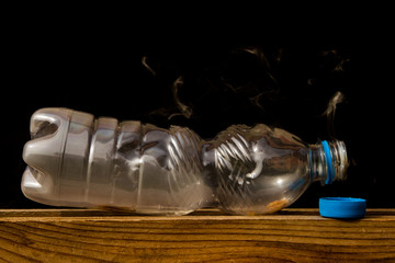 Fototapeta na wymiar close up of a plastic bottle slowly burning producing smoke and consuming itself as a symbol of recycling and environmental pollution