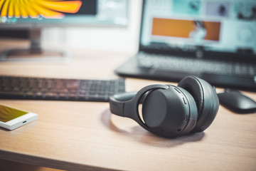 Workspace media concept: Black wireless headphones, keyboard and mouse on wooden desk - obrazy, fototapety, plakaty