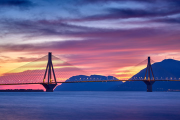 Sunset view on the bridge near Patras. Suspension bridge crossing Corinth Gulf strait, Greece, Europe. Second longest cable-stayed bridge in the world. Dramatic red sky under a Rion-Antirion Bridge.