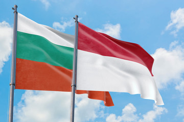 Indonesia and Bulgaria flags waving in the wind against white cloudy blue sky together. Diplomacy concept, international relations.