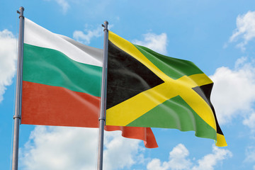 Jamaica and Bulgaria flags waving in the wind against white cloudy blue sky together. Diplomacy concept, international relations.
