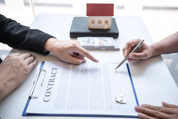 Sale purchase contract to buy a house, Real estate agent are presenting home loan and giving keys to customer after signing contract to buy house with approved property application form