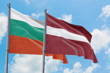 Latvia and Bulgaria flags waving in the wind against white cloudy blue sky together. Diplomacy concept, international relations.
