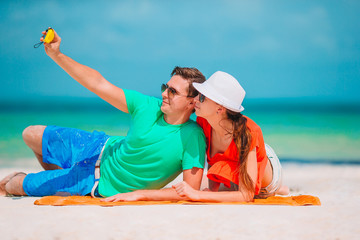 Happy couple taking a self photo on a beach on holidays