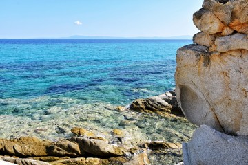 Seascape of rocky beach with azure sea water in sunny day. Amazing natural beach with white stones and turquoise water. crystal clear sea with sun reflection. Halkidiki Greece Blue Flag Beach