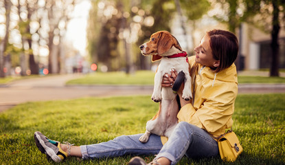 Cheerful woman with dog sitting in park