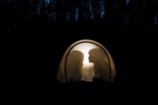 Children telling bedtime stories in a camping tent at night