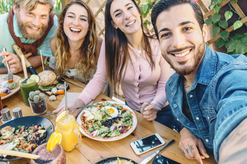 Happy friends taking selfie with mobile smartphone while lunching in coffee brunch restaurant - Young trendy people having fun eating together - Youth lifestyle food culture concept - obrazy, fototapety, plakaty