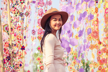 Asian tourist woman wearing hat , standing  among colorful tung flag (traditional north-eastern Thai craft) smiling and looking at camera.