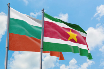 Suriname and Bulgaria flags waving in the wind against white cloudy blue sky together. Diplomacy concept, international relations.