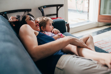 Mother with female child indoor on the couch cuddling