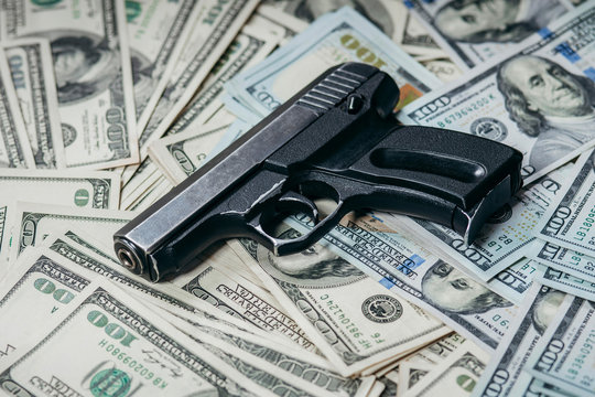 Detail of gun with bullet on US dollar 100 bill banknotes