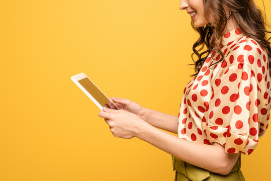 cropped view of smiling young woman using digital tablet isolated on yellow