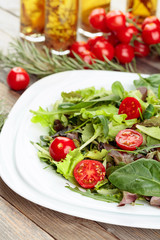 Fresh mixed salad with cherry tomatoes on white plate.