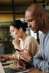 Image of multiethnic young coworkers working on laptops in office