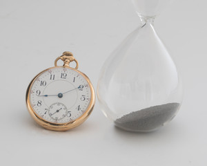 Antique pocket watch with an old hour glass used for telling time,