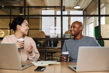 Image of multiethnic young coworkers working on laptops in office