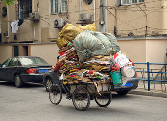 Man riding tricycle with charge of paper to be recycled in Shanghai.