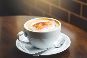 close up modern hot black coffee the cappuccino on wood background with coffee bubble foam pattern and texture in white cup looking and feel so delicious on glasses table in coffee shop.