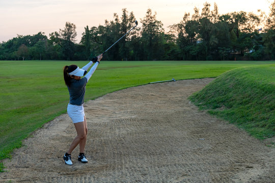 Golfer sport course golf ball fairway.  People lifestyle woman playing game golf and hitting out of sand trap go on green grass.  Asia female player game shot in summer.  Healthy and Sport outdoor