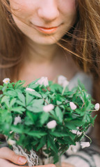 Fototapeta premium pretty girl holding white spring flowers walking through the green forest