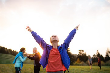 A portrait of young woman with large group of people doing exercise in nature.