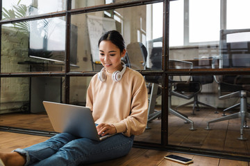 Image of young beautiful asian woman working on laptop in office