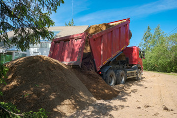 the truck pours sand on the construction site