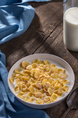 Breakfast with cereal. Flakes with milk. A plate of cereal with milk on a old wooden table. Perfect for breakfast. Free space for text.