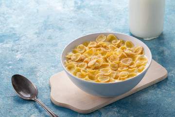 Breakfast with cereal. Flakes with milk. A plate of cereal with milk on a blue table. Perfect for breakfast. Free space for text.