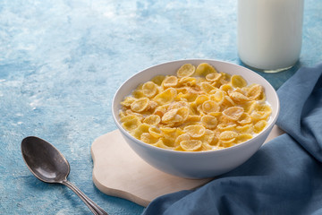 Breakfast with cereal. Flakes with milk. A plate of cereal with milk on a blue table. Perfect for breakfast. Free space for text.