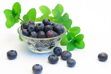 Still life photos of blueberries and green leaves on a white background.