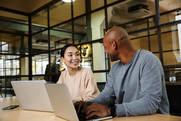 Image of multiethnic young coworkers working on laptops in office