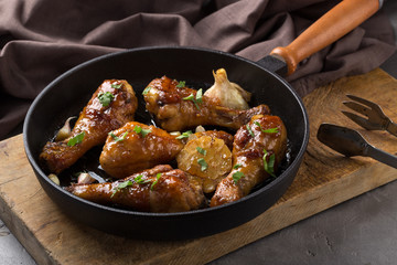 Chicken thighs with grilled vegetables. Chicken served in a frying pan on an old wooden table. Chicken with lime, zucchini, eggplants, onions and garlic. Close-up shot. Free space for text.