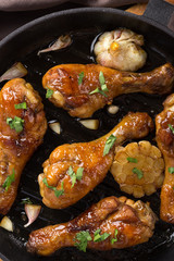 Chicken thighs with grilled vegetables. Chicken served in a frying pan on an old wooden table. Chicken with lime, zucchini, eggplants, onions and garlic. Close-up shot. Free space for text.