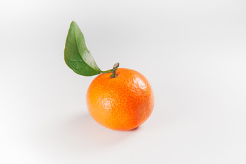 A little orange with leaves on a white background.