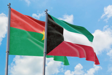 Kuwait and Burkina Faso flags waving in the wind against white cloudy blue sky together. Diplomacy concept, international relations.