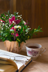 still life with bouquet, cup of coffee, glasses and open book. Wooden table, copy space for your text