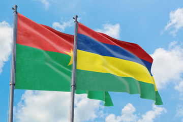 Mauritius and Burkina Faso flags waving in the wind against white cloudy blue sky together. Diplomacy concept, international relations.