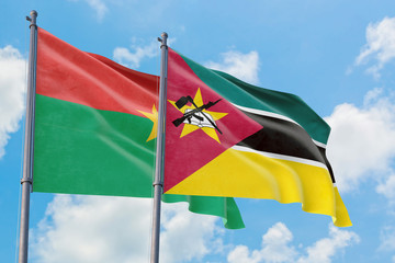 Mozambique and Burkina Faso flags waving in the wind against white cloudy blue sky together. Diplomacy concept, international relations.