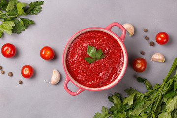 Tomato soup with parsley, onion and garlic on gray background. Comfortable food. Rustic style. Copy space. .