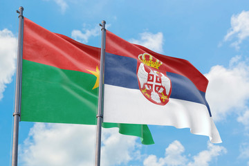 Serbia and Burkina Faso flags waving in the wind against white cloudy blue sky together. Diplomacy concept, international relations.